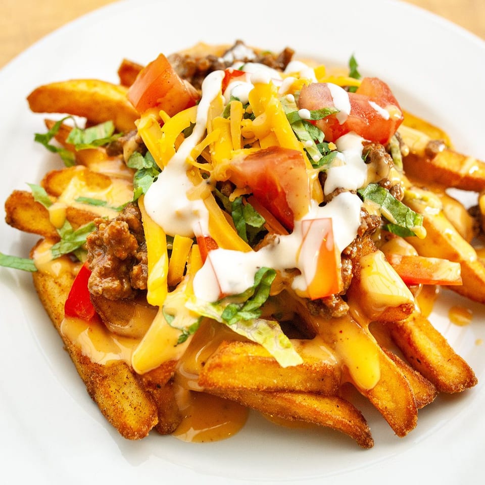 Golden fries topped with ground beef, melted cheese, diced tomatoes, lettuce, and sour cream.