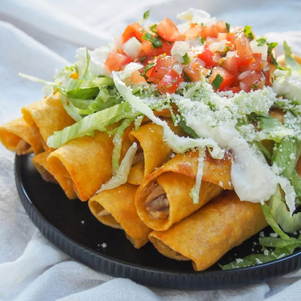 Crispy taquitos topped with shredded lettuce, pico de gallo, sour cream, and cotija cheese.